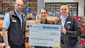 Die stellvertretenden Marktleiter Marcel Wallasch (links) und Sascha Struckmann übergeben den symbolischen Scheck an Mona Gharib.